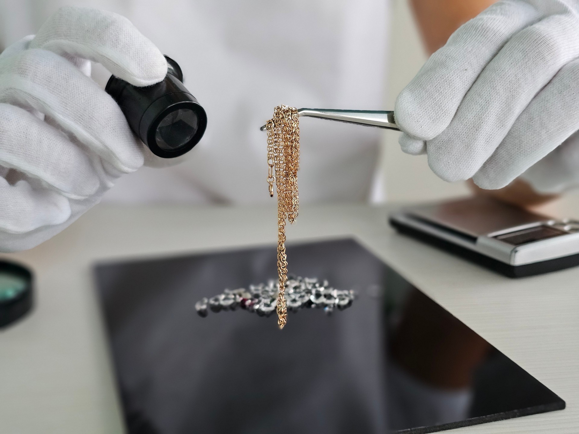 Jewelry appraiser examining a delicate gold chain with precision tools in a well-lit office